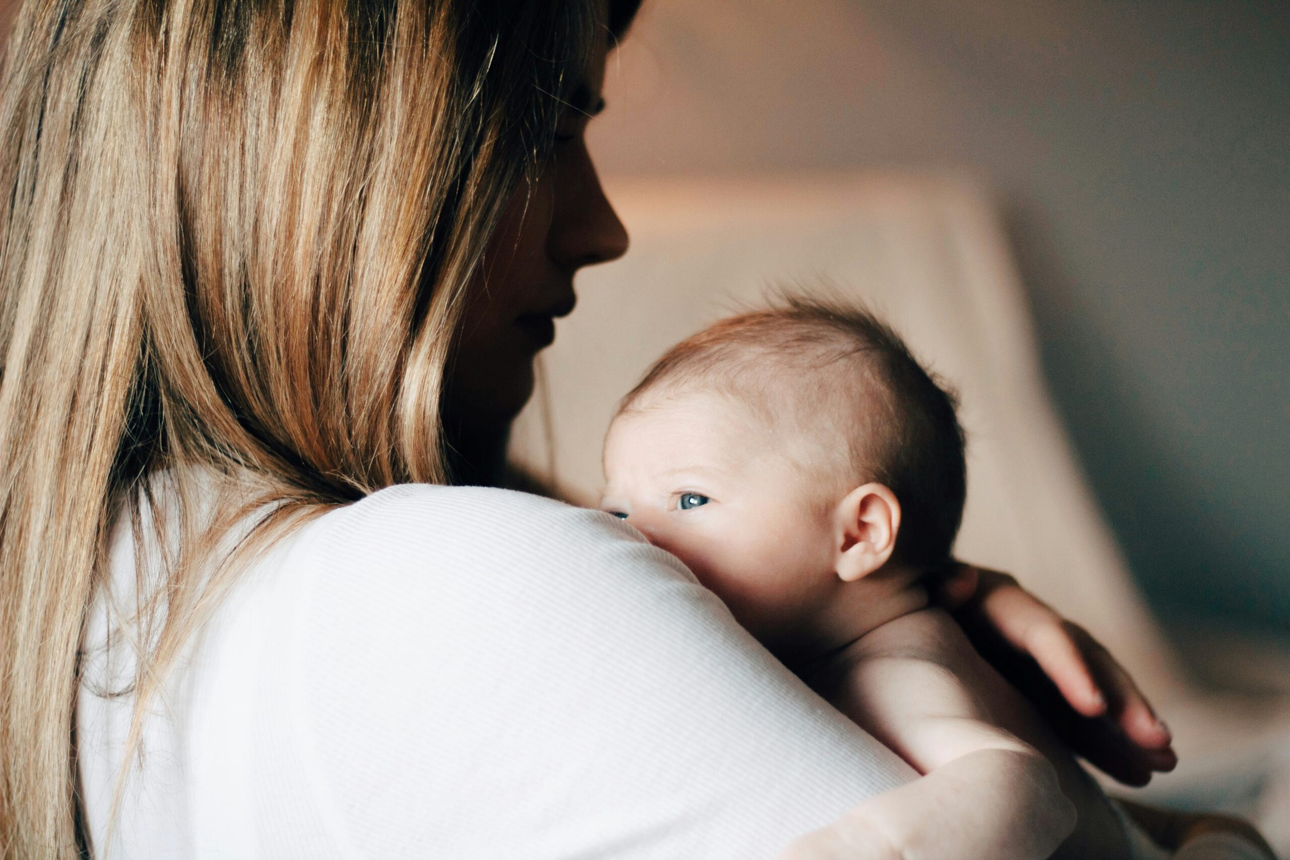 Adulto che accompagna con delicatezza la postura e i movimenti di un bambino nei primi mesi.