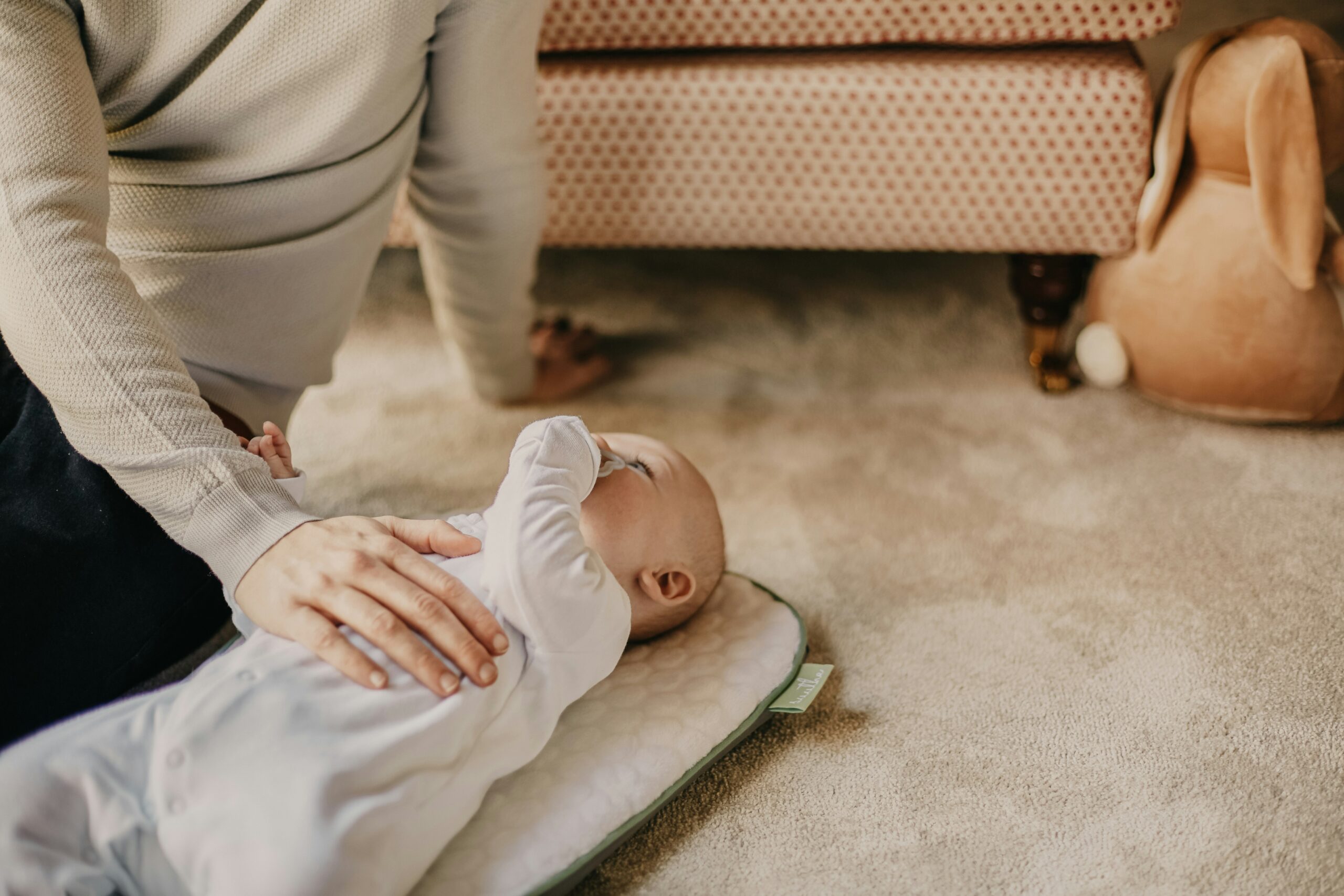 Bambino nei primi mesi su un tappeto, accompagnato da un adulto durante un momento di gioco e movimento