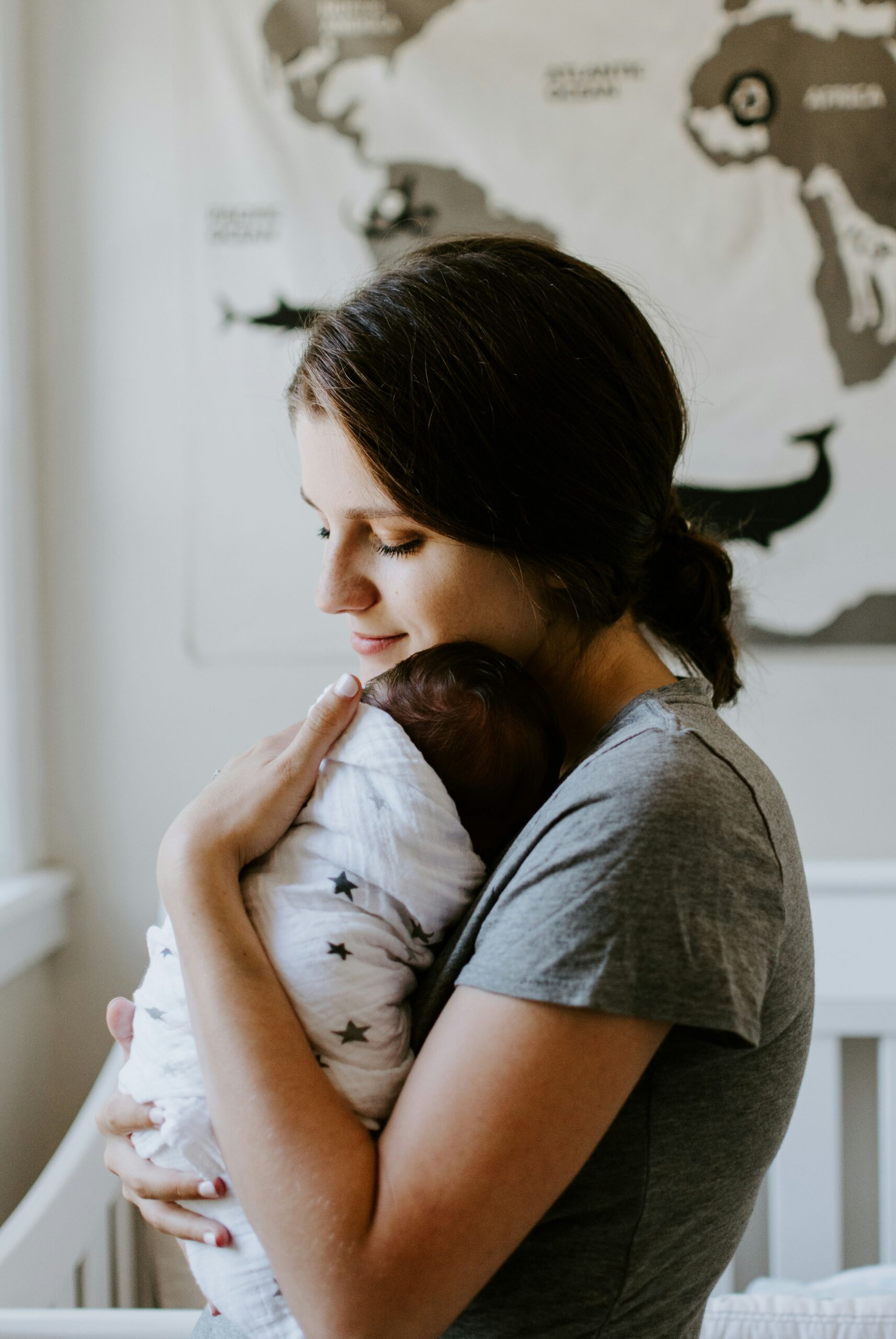 Un genitore tiene in braccio un neonato mentre parla con un’osteopata pediatrica in uno studio luminoso.